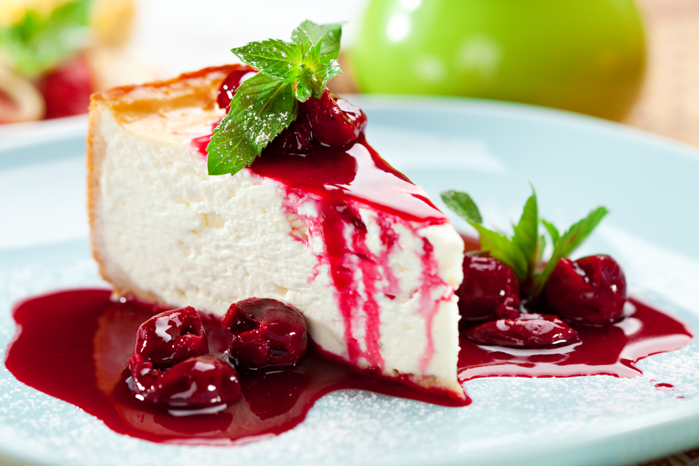 Picture of cheesecake with raspberry dessert sauce drizzled over it.