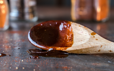 Picture of wooden spatula with barbecue sauce on it.